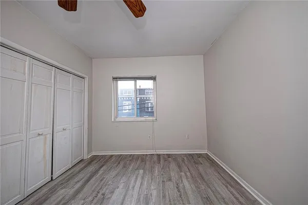 an empty room with wooden floor cabinet and windows