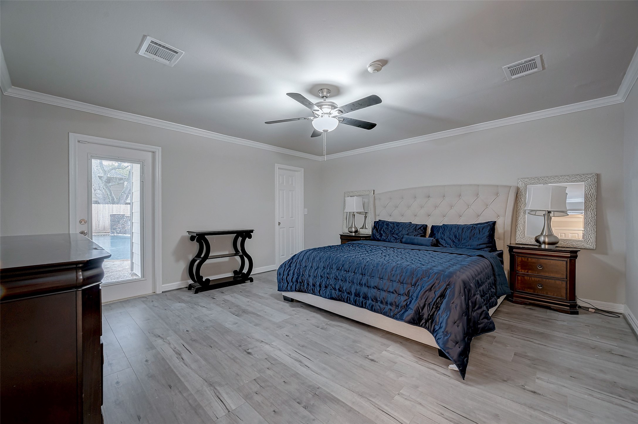 919 Mockingbird Way Sugar Land, TX 77478 - Photo 14 of 41 Primary bedroom features a large bed with a tufted headboard, modern wood flooring.