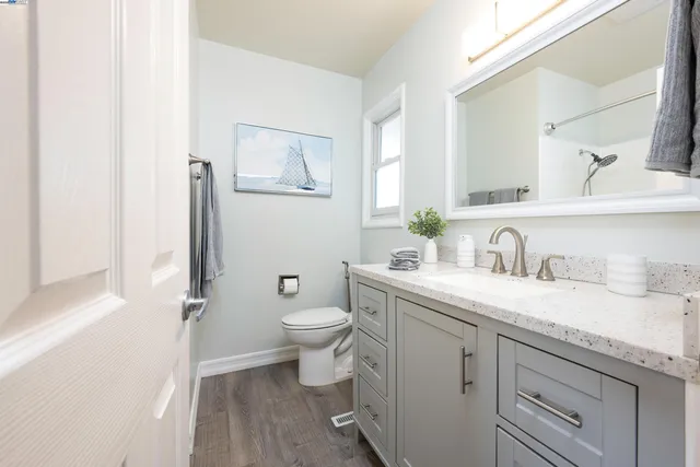 a bathroom with a granite countertop toilet sink and mirror