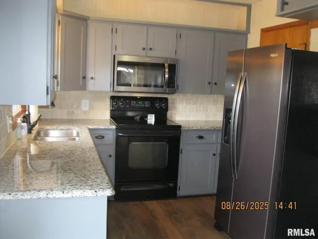 a kitchen with stainless steel appliances granite countertop a refrigerator a stove and a sink
