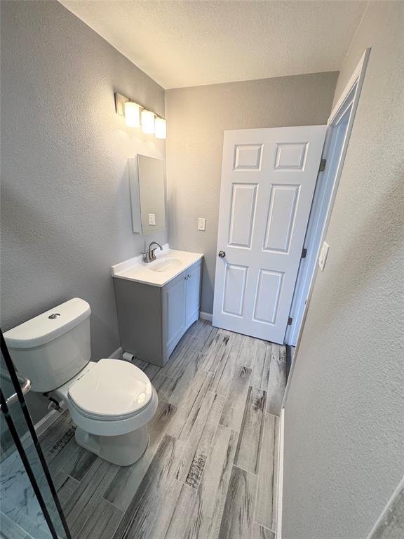 1736 Ransom Terrace Fort Worth, TX 76112 - Photo 11 of 27 Bathroom featuring wood-finish tile flooring, a white vanity with a rectangular sink, a wall-mounted medicine cabinet, and a four-light vanity fixture