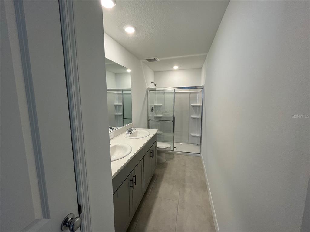 2995 Skyline Loop Kissimmee, FL 34758 - Photo 24 of 46 a bathroom with a granite countertop sink a mirror and a shower