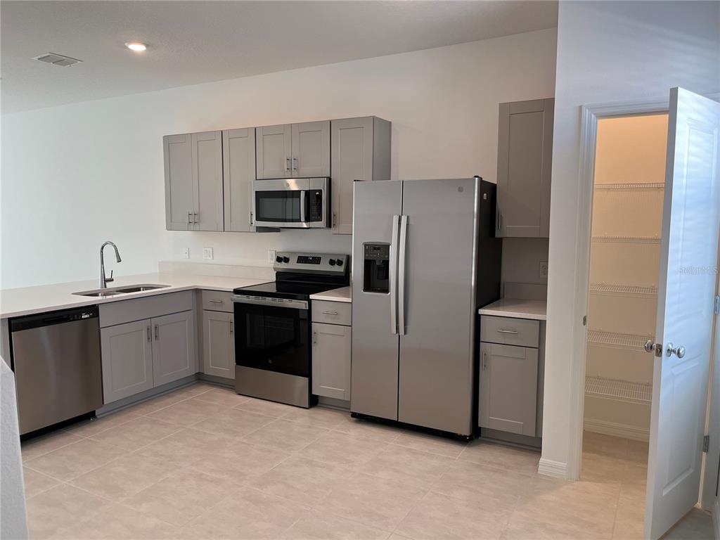 2995 Skyline Loop Kissimmee, FL 34758 - Photo 4 of 46 a kitchen with stainless steel appliances white cabinets and a refrigerator