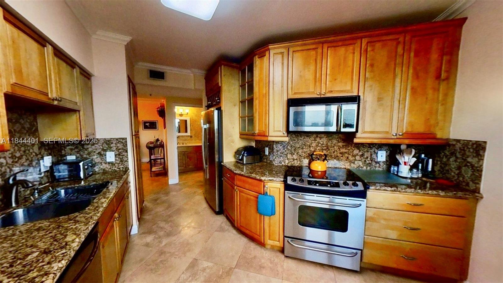 2425 Southwest 27th Avenue, Unit 701 Miami, FL 33145 - Photo 38 of 57 a kitchen with stainless steel appliances granite countertop wooden cabinets a stove top oven a sink and dishwasher