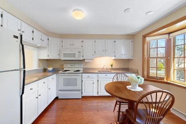 a kitchen with stainless steel appliances granite countertop a stove a refrigerator a white table and chairs