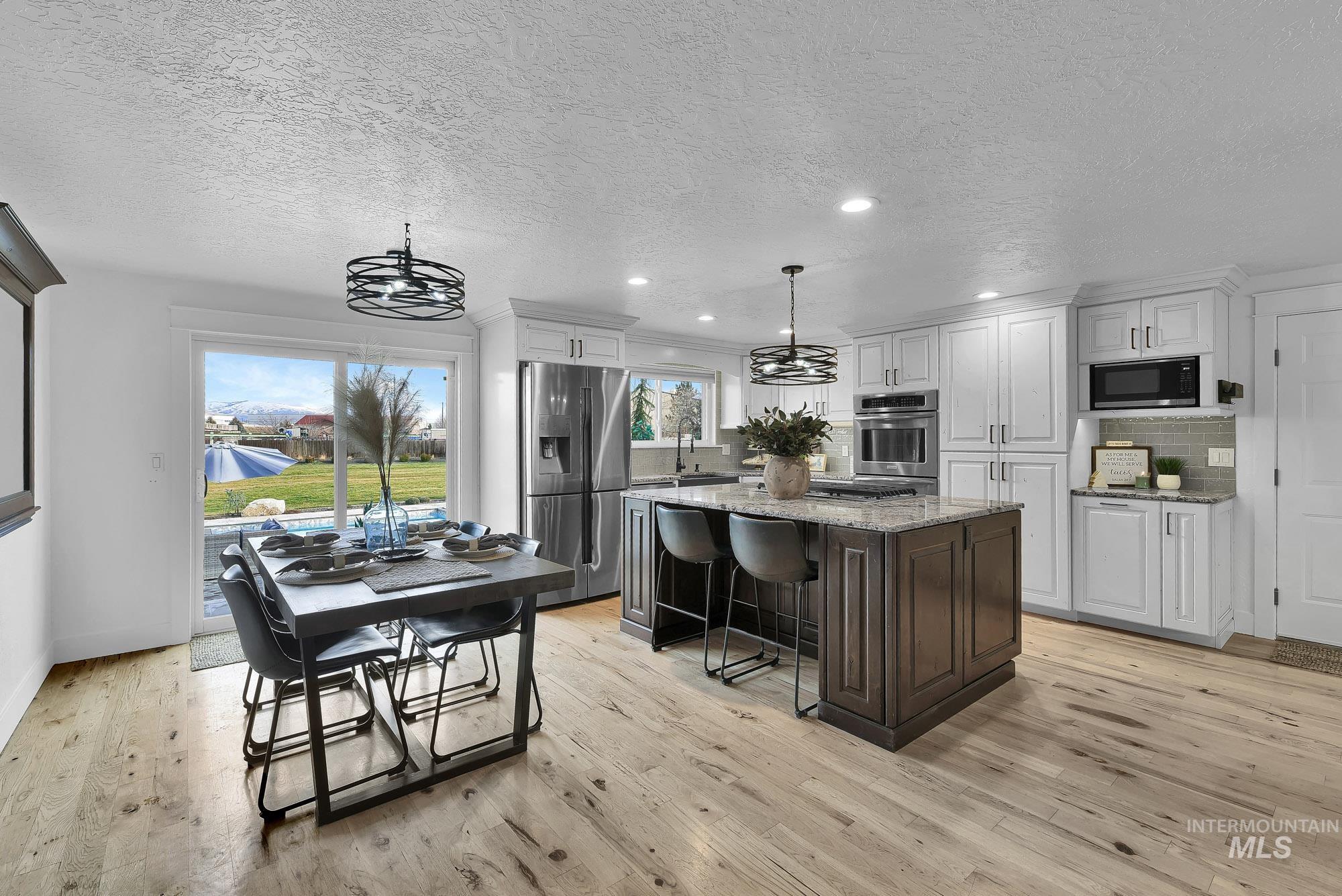3630 Beverly Street Boise, ID 83709 - Photo 11 of 50 Kitchen featuring light stone countertops, a textured ceiling, a breakfast bar, a center island, and appliances with stainless steel finishes