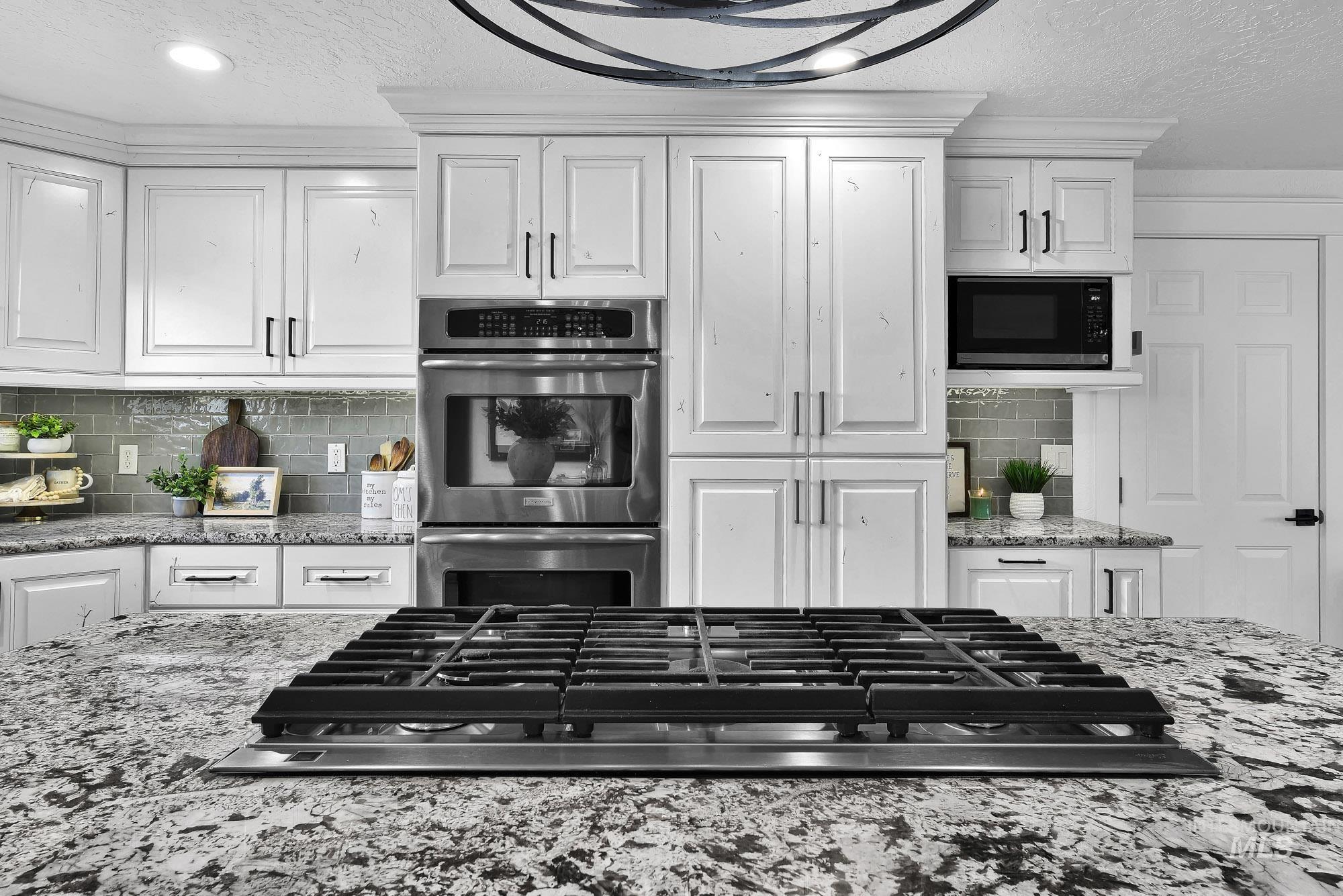 3630 Beverly Street Boise, ID 83709 - Photo 14 of 50 Kitchen featuring light stone counters, a textured ceiling, appliances with stainless steel finishes, white cabinetry, and decorative backsplash