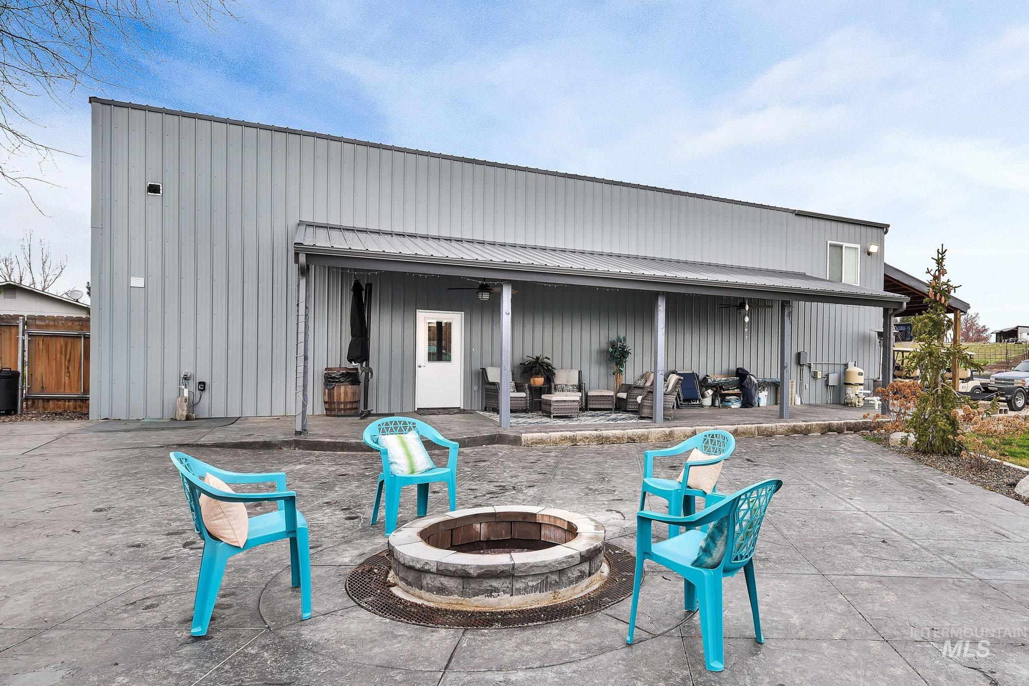 3630 Beverly Street Boise, ID 83709 - Photo 47 of 50 Back of house with a patio area, a metal roof, a ceiling fan, a fire pit, and board and batten siding