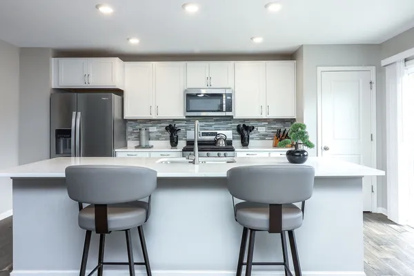 a kitchen with stainless steel appliances a sink a stove a table and chairs