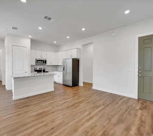 a view of kitchen with kitchen island wooden floor center island and stainless steel appliances