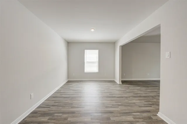 a view of an empty room with wooden floor and window