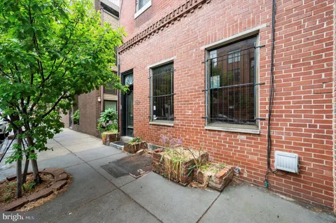 a view of a brick house with potted plants in front of door