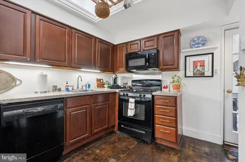 a kitchen with stainless steel appliances granite countertop a stove top oven a sink dishwasher and a microwave oven on the blue kitchen countertops