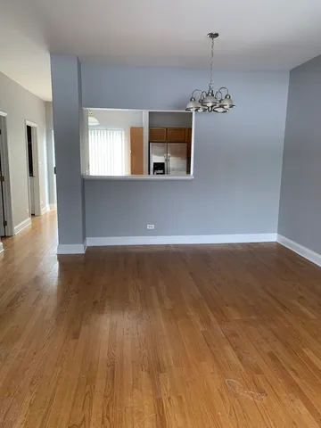 a view of a room with wooden floor chandelier and a kitchen