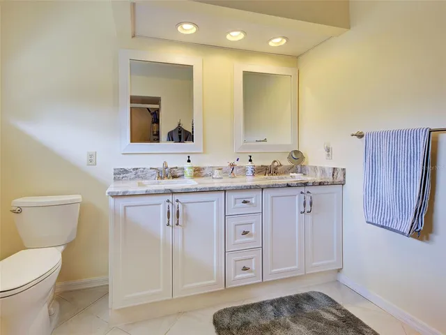 a bathroom with a granite countertop toilet sink and mirror