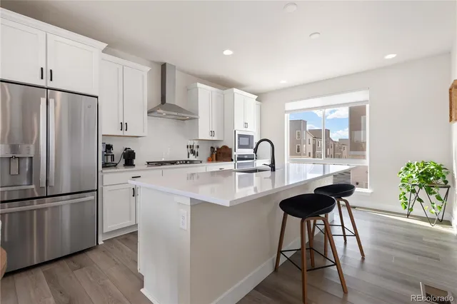 a kitchen with stainless steel appliances a refrigerator a sink a stove a refrigerator and wooden floor