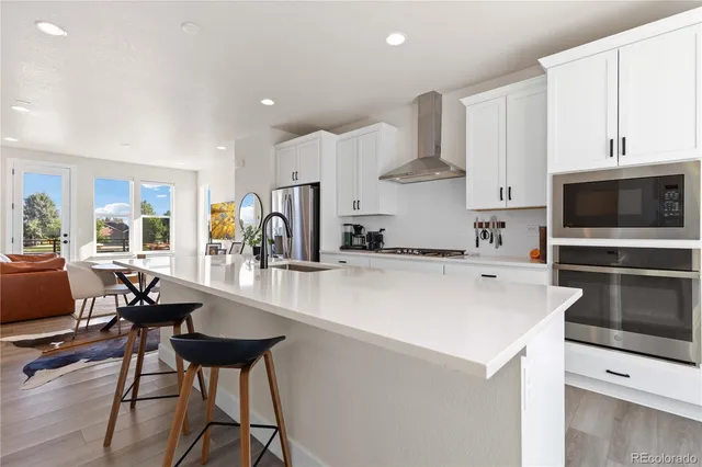 a kitchen with stainless steel appliances a stove a sink a microwave and a refrigerator