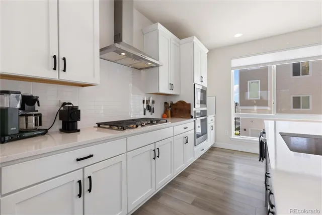 a kitchen with cabinets wooden floor and stainless steel appliances