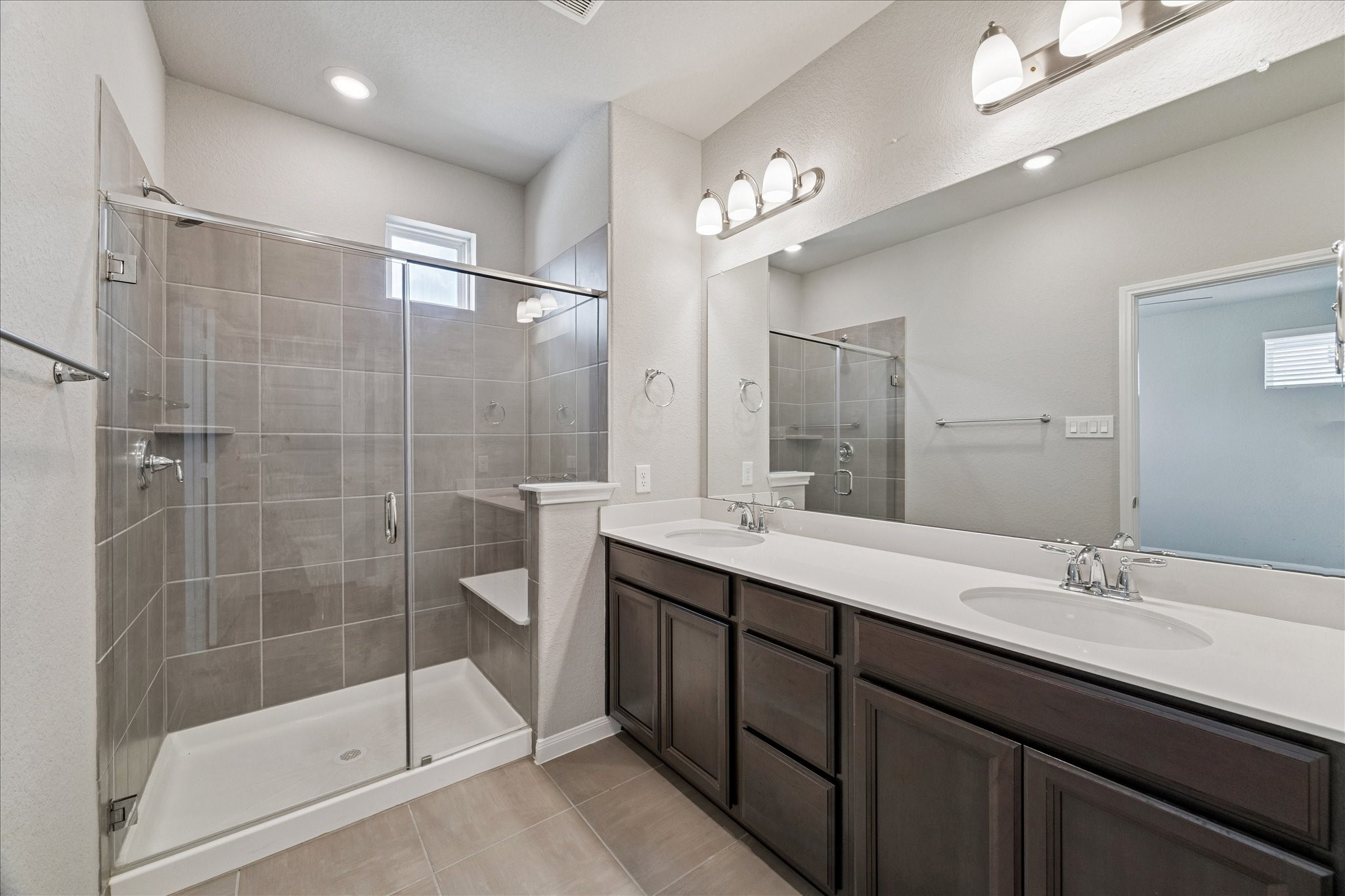 5502 Cuerta Street Houston, TX 77023 - Photo 13 of 25 Primary bathroom with dual sinks, a walk-in shower with a seat, and plenty of storage space.