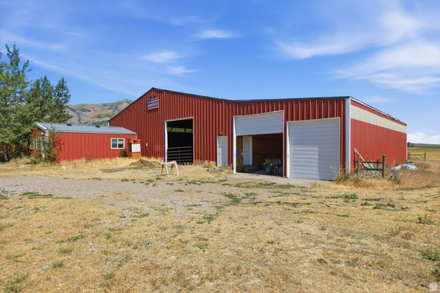 1634 West Arimo Road Arimo, ID 83214 - Photo 32 of 89 Expansive red metal barn structure with multiple bay doors and an attached smaller red metal outbuilding