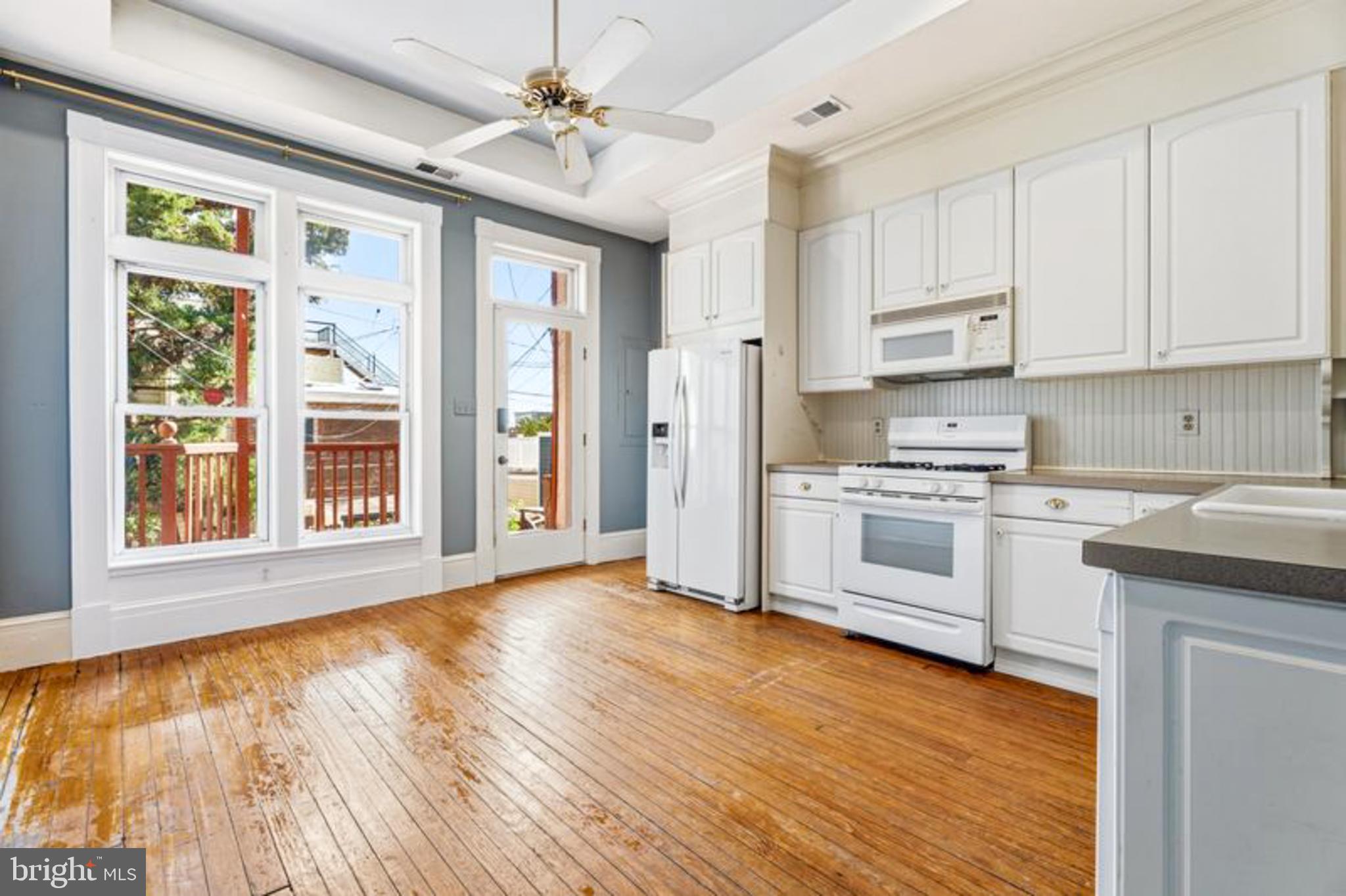2033 East Pratt Street Baltimore, MD 21231 - Photo 20 of 61 a kitchen with stainless steel appliances granite countertop a stove top oven a refrigerator a sink and white cabinets with wooden floor next to windows