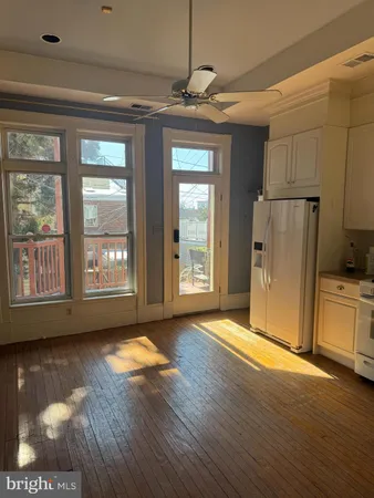 a view of an empty room with window and wooden floor