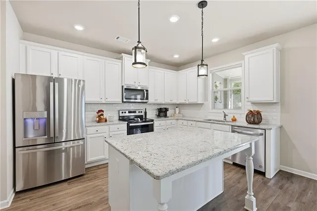 a kitchen with stainless steel appliances granite countertop a refrigerator a sink dishwasher a stove and white cabinets