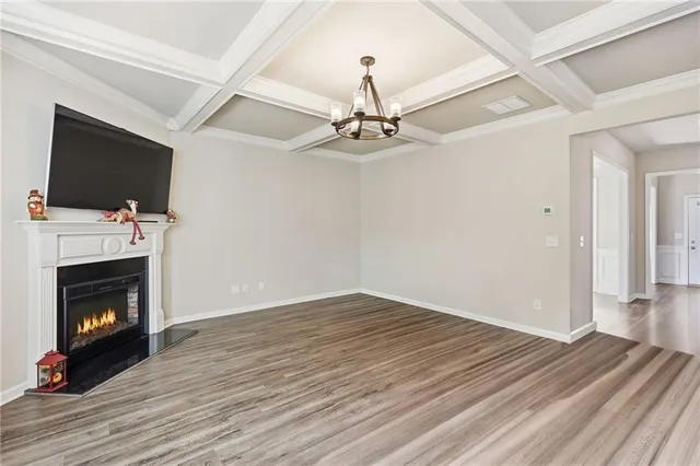 a view of an empty room with wooden floor fireplace and a window