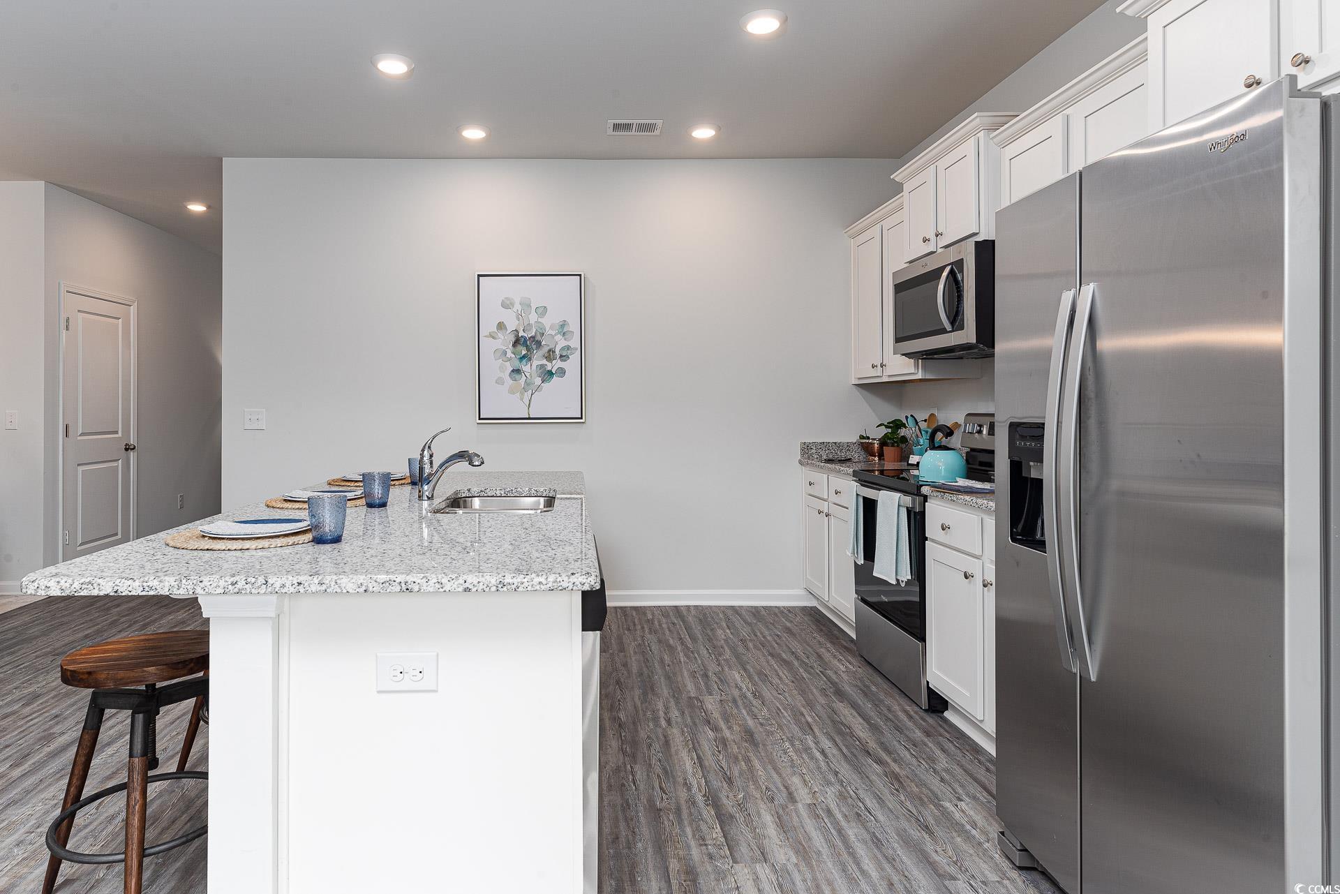 1029 St Martin Street Georgetown, SC 29440 - Photo 4 of 23 Kitchen featuring appliances with stainless steel finishes, white cabinetry, a kitchen bar, recessed lighting, and dark wood finished floors