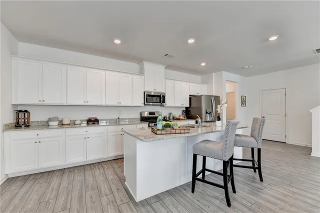 a kitchen with stainless steel appliances granite countertop a table chairs microwave and cabinets