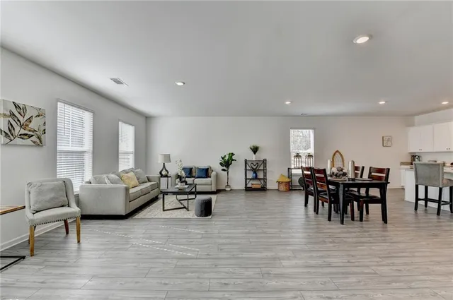 a living room with furniture and a dining table with wooden floor