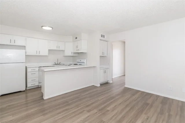 a kitchen with wooden floors white cabinets and appliances