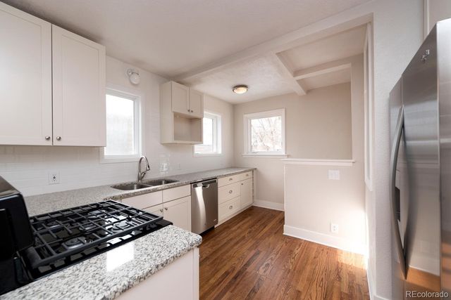 a kitchen with granite countertop a stove a sink dishwasher and a refrigerator with wooden floor
