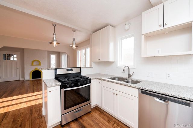 a kitchen with stainless steel appliances a stove a sink a stove and white cabinets