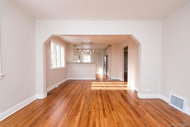 a view of empty room with wooden floor and fan