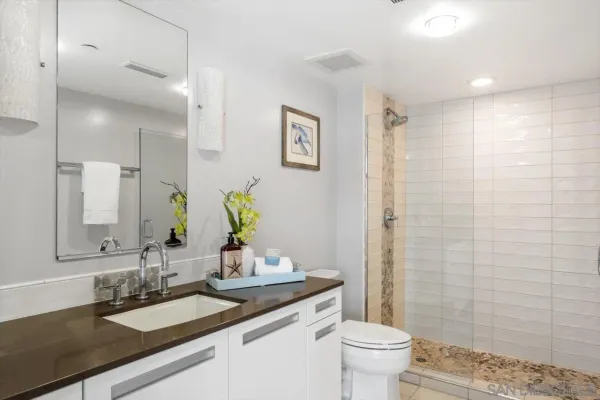 a bathroom with a granite countertop sink a toilet and a mirror