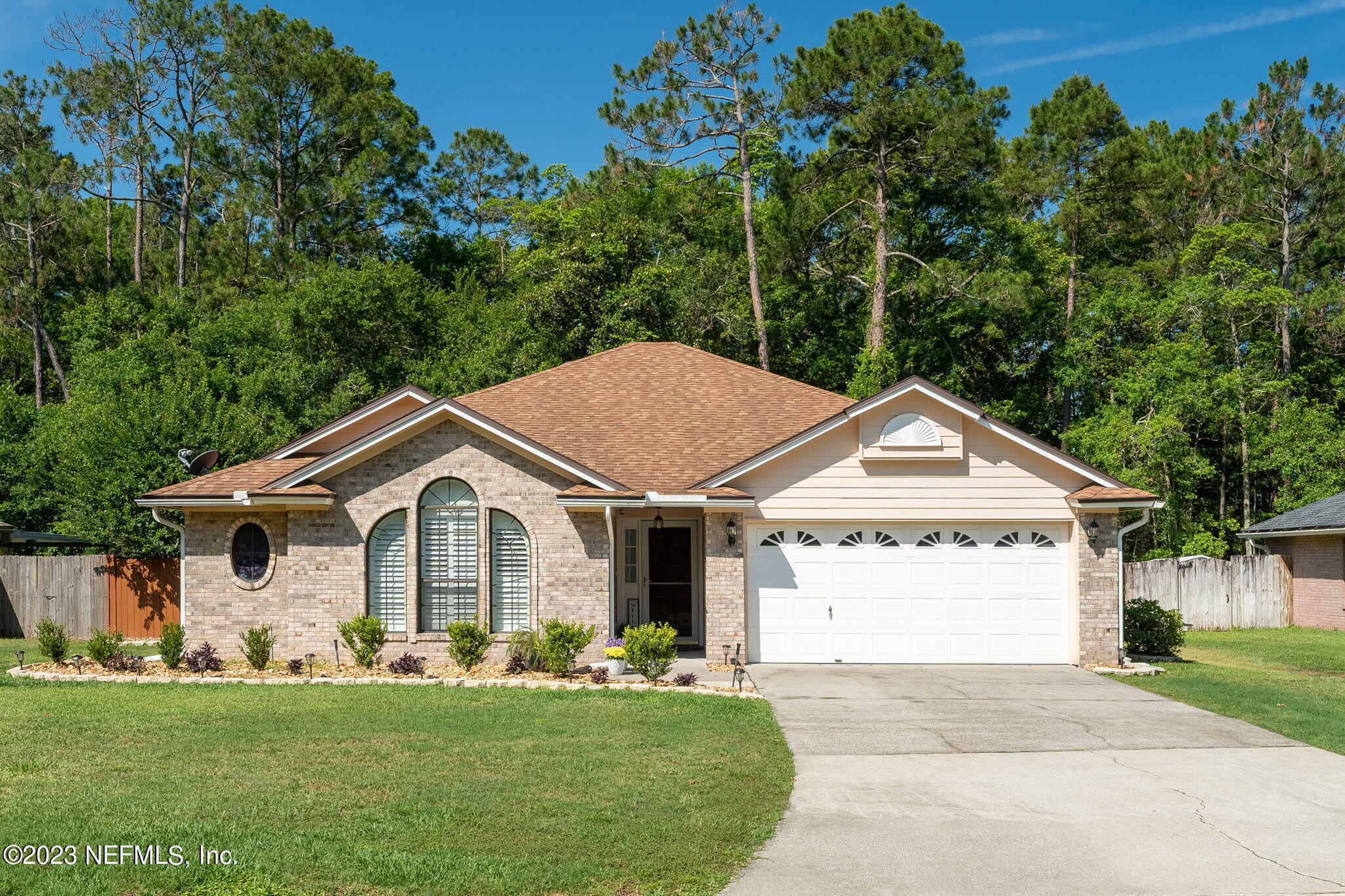 a view of a white house with a big yard and large trees