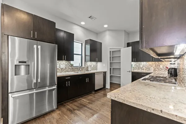 a kitchen with stainless steel appliances kitchen island granite countertop a refrigerator and a sink