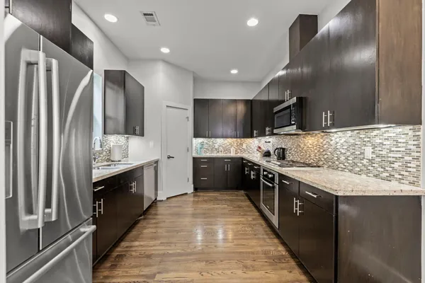 a large kitchen with stainless steel appliances double sink and a refrigerator