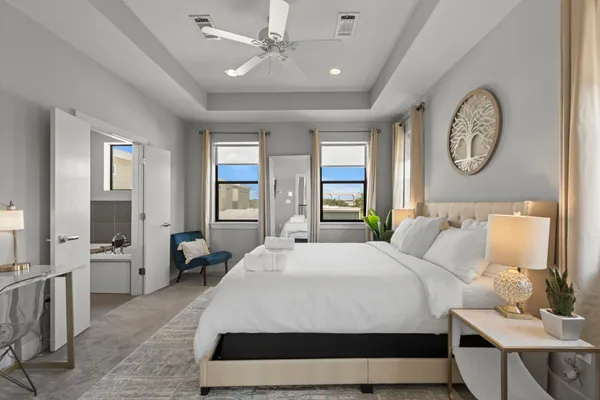 a spacious bedroom with a bed a mirror and a large window