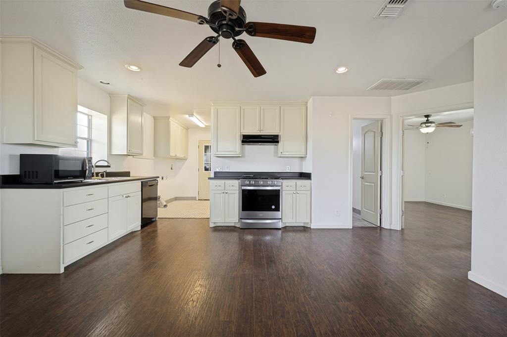 8400 Holder Road Northlake, TX 76247 - Photo 30 of 36 Open-concept living space with dark wood-finish flooring, white cabinetry, dark countertops, and stainless steel appliances