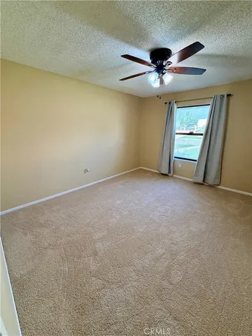 an empty room with windows and fan