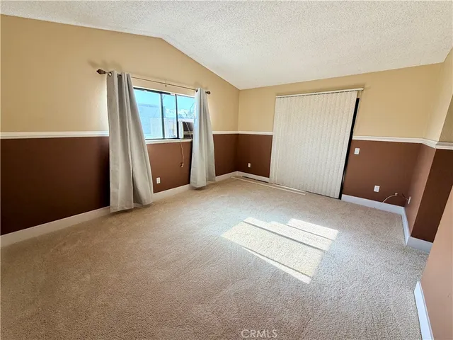 an empty room with windows and refrigerator