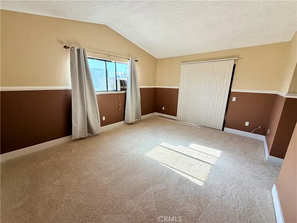 an empty room with windows and refrigerator