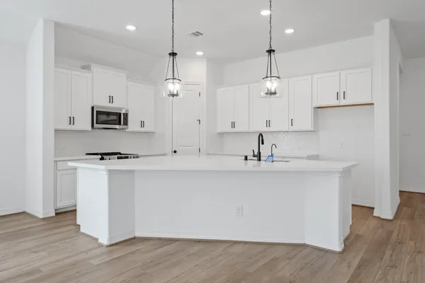 a large kitchen with stainless steel appliances a large counter top a stove a sink and a refrigerator