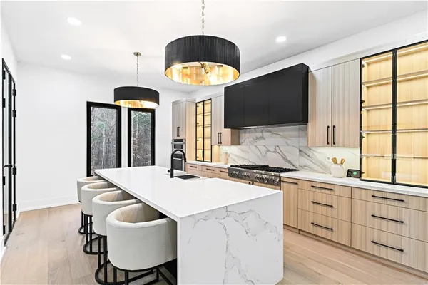 a kitchen with stainless steel appliances kitchen island granite countertop a refrigerator a stove and a sink with wooden floor