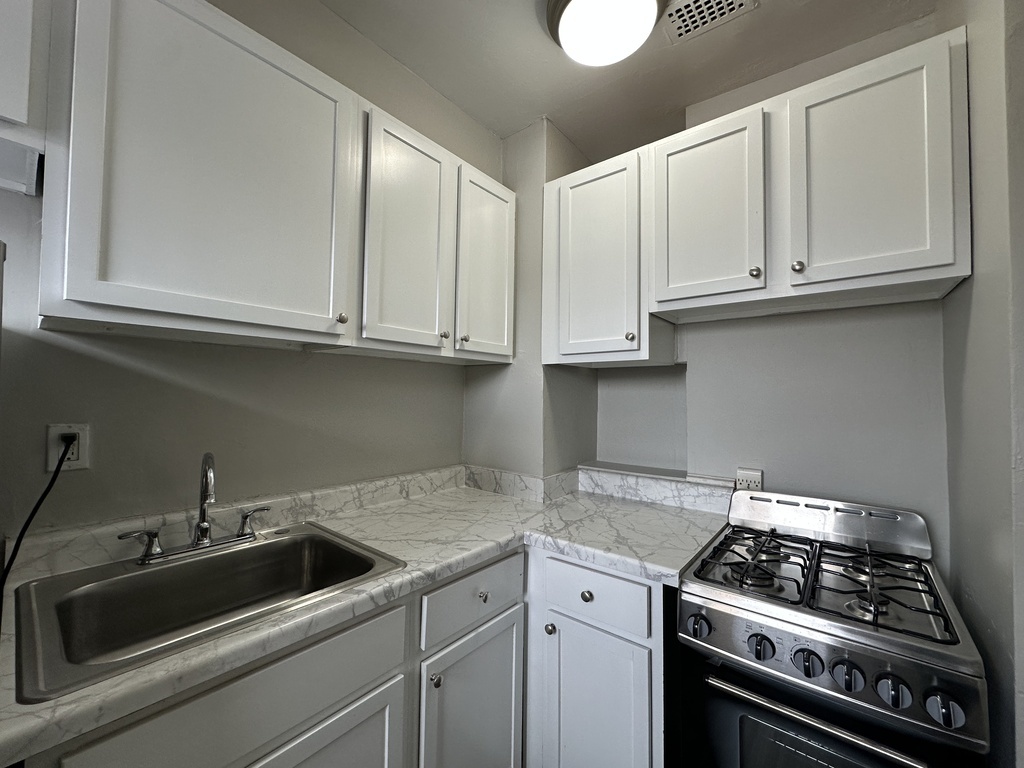 661 West Sheridan Road, Unit 601 Chicago, IL 60613 - Photo 3 of 20 a kitchen with granite countertop white cabinets and a stove top oven