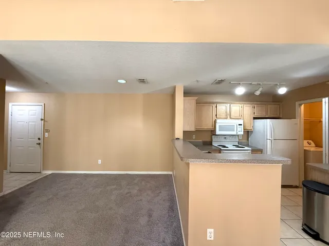 a kitchen with kitchen island stainless steel appliances a sink a stove a refrigerator a microwave a dining table and chairs