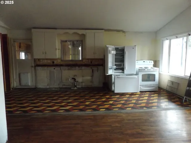 a view of a kitchen with wooden floor and a window