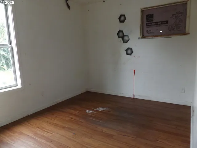 a view of an empty room with wooden floor and windows